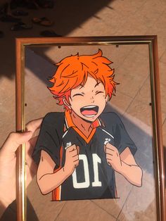 a person holding up a drawing of an orange haired boy with his mouth open and tongue out