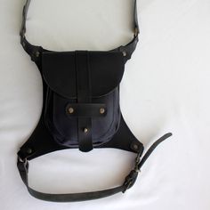 a black leather shoulder bag sitting on top of a white sheet