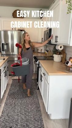 a woman is standing in the kitchen with her hand on the cabinet and holding a cleaning mop