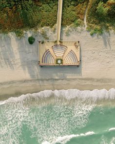 an aerial view of the beach and ocean with a gazebo in the sand area