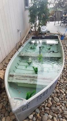 a small boat sitting on top of a pebble covered ground next to a building