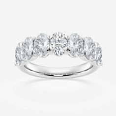 a white gold ring with five stones on the side and two rows of diamonds around it