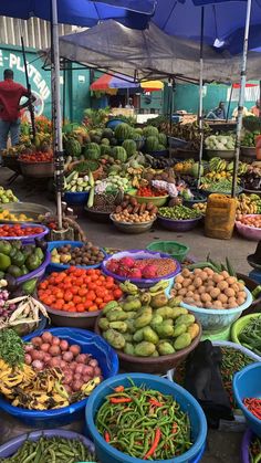 an open air market with lots of fruits and veggies on the tables under umbrellas