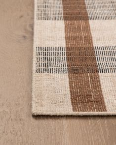 a brown and white checkered rug on top of a wooden floor