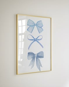 a framed photo with blue bows hanging on the wall in front of a white wall