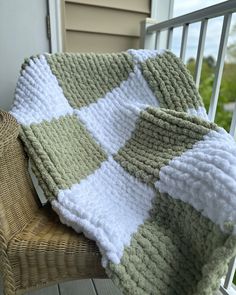 a green and white blanket sitting on top of a wooden chair