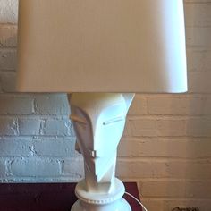 a table lamp with a white face on it and a beige shade over the base