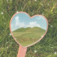 a heart shaped mirror sitting in the grass