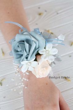 a woman's hand holding a wrist corsage with flowers