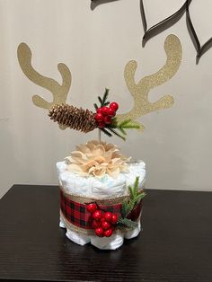 a christmas cake decorated with reindeer antlers and pine cones on a table next to a wall