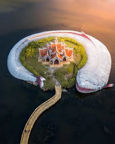 an island in the middle of water with a building on it's side and a walkway leading up to it