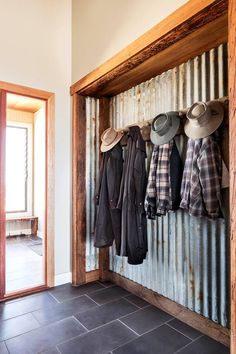 the interior french doors are open to show hats and coats hanging from hooks on an old door