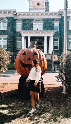 a woman standing in front of a giant pumpkin