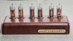 four tubes with numbers on them are sitting in a wooden holder that says paint indicator