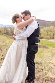 a bride and groom kissing in the field