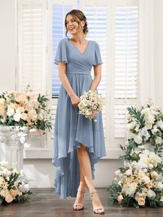 a woman standing in front of flowers wearing a gray bridesmaid dress with short sleeves