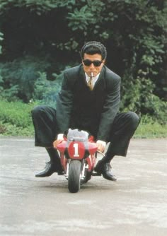 a man riding on the back of a red motorcycle