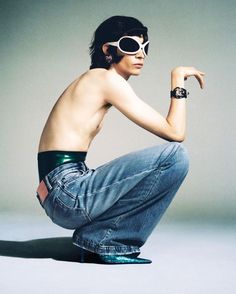 a shirtless man in jeans and goggles poses for a photo with his hand on his hip