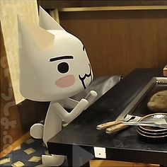 a paper cat sitting on top of a table next to a plate and knifes