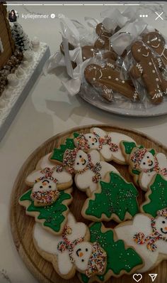 cookies decorated with icing and sprinkles on a wooden platter next to a plate of cookies