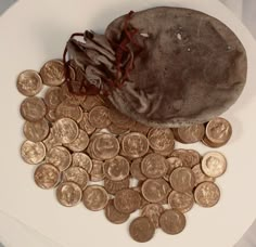 a pile of gold coins sitting on top of a white table next to a bag