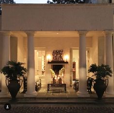 the front entrance to a house lit up at night with potted plants on either side