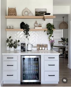 a kitchen with white cabinets and open shelving above the stove top is filled with potted plants