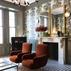 a living room with two chairs and a table in front of a mirror on the wall