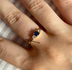 a woman's hand with a diamond and blue sapphire ring