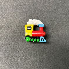 a small toy train is sitting on the floor next to a gray carpeted surface