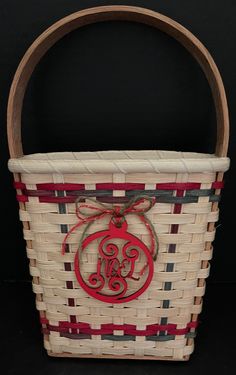 a white basket with a red monogrammed initial on the side and a wooden handle