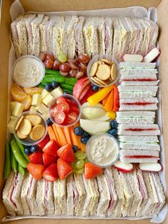 a box filled with sandwiches, fruit and crackers on top of eachother