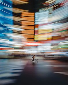 a blurry photo of a bicyclist in the middle of an urban street