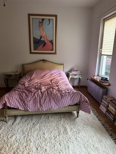 a bedroom with a bed, rug and painting on the wall