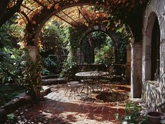 an outdoor dining area with tables and chairs under a pergolated roof, surrounded by greenery