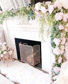 a white fireplace with pink flowers and greenery