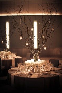 the centerpieces are decorated with branches and lit candles for an elegant wedding reception