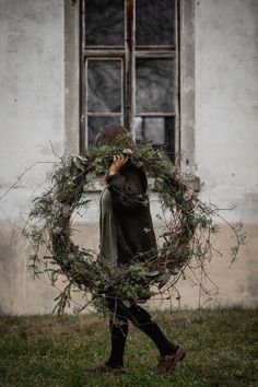 a woman holding a wreath in front of her face