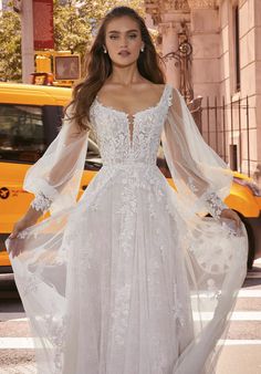 a woman in a white wedding dress standing on the street