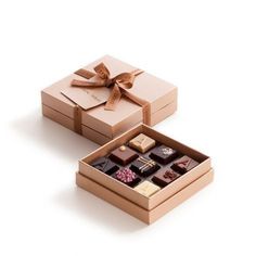 an open box with assorted chocolates and a bow on the top is shown