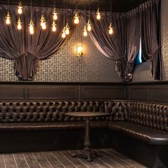 a booth with leather couches and lights hanging from the ceiling