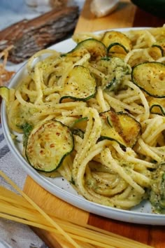 pasta with zucchini and pesto on a white plate next to yellow chopsticks