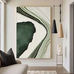 an abstract painting hangs on the wall above a couch in front of a large window