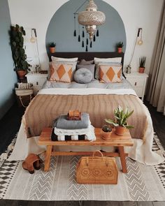 a bedroom with a bed, rugs and plants on the side table in front of it