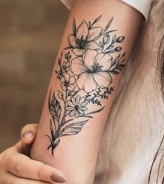 a woman's arm with flowers and leaves tattooed on the side of her arm