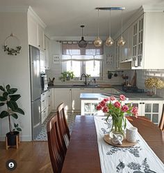 a table with flowers on it in a kitchen next to a refrigerator and sink,