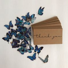 a bunch of blue butterflies sitting on top of a table next to a thank card