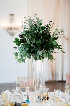 a vase filled with flowers sitting on top of a table covered in plates and glasses