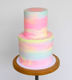 a multi - colored cake on a wooden stand