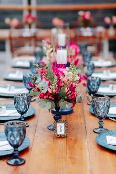 a wooden table topped with lots of blue and white dishes filled with flowers on top of it